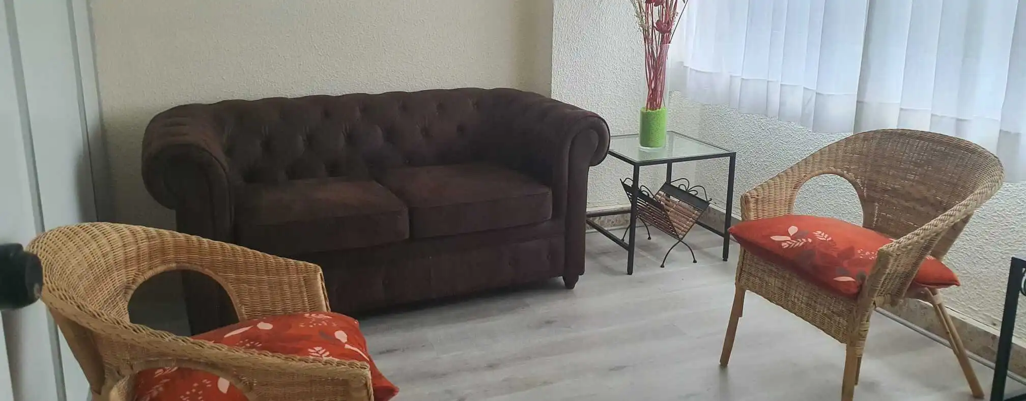Fotografía de la zona de terapia del gabinete, con un sofa y dos sillas.